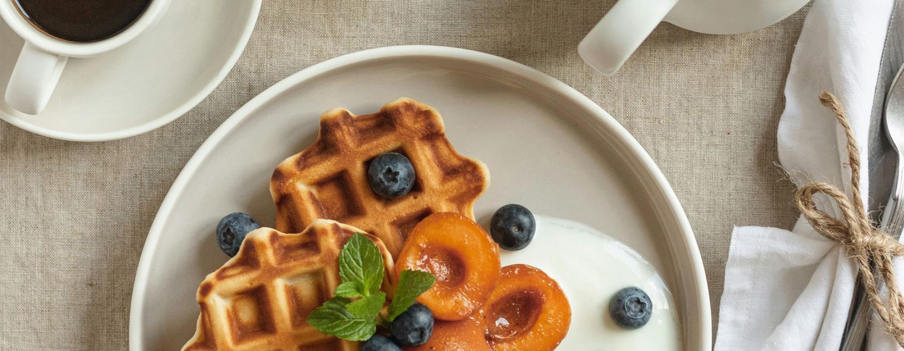 a plate of blueberries and waffles and a cup of coffee